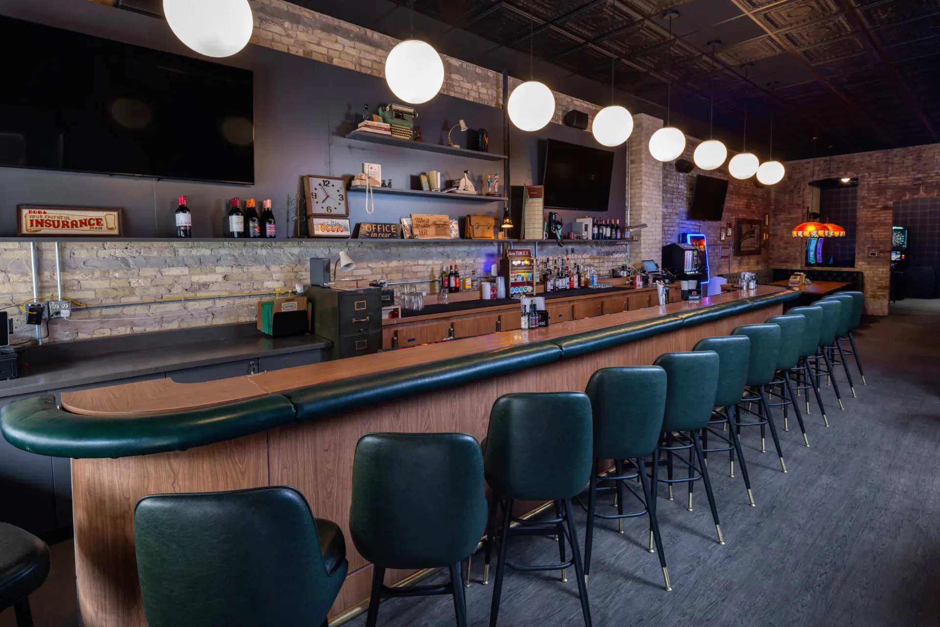The bar at Your Office in Milwaukee, Wisconsin with green stools and modern dive bar decor