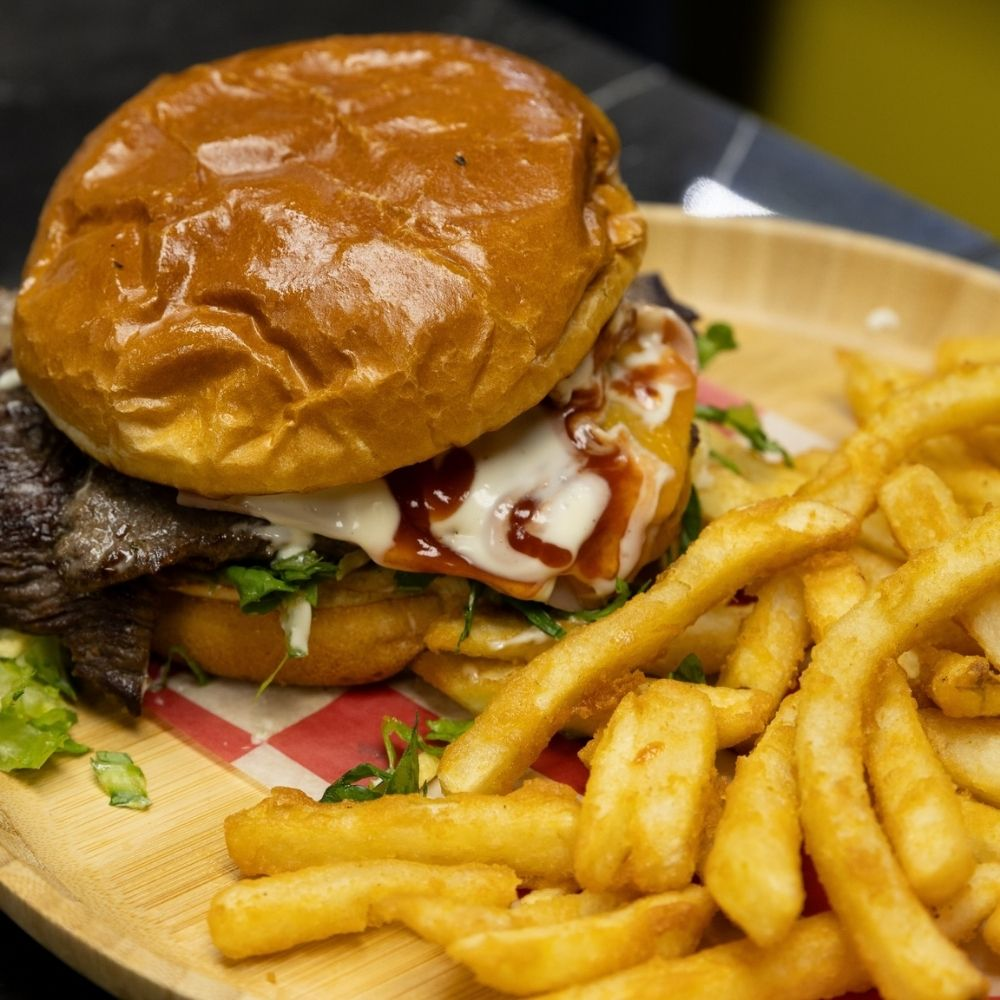 Burger and fries served on a wood platter at Pa'Que Roberto in Madison
