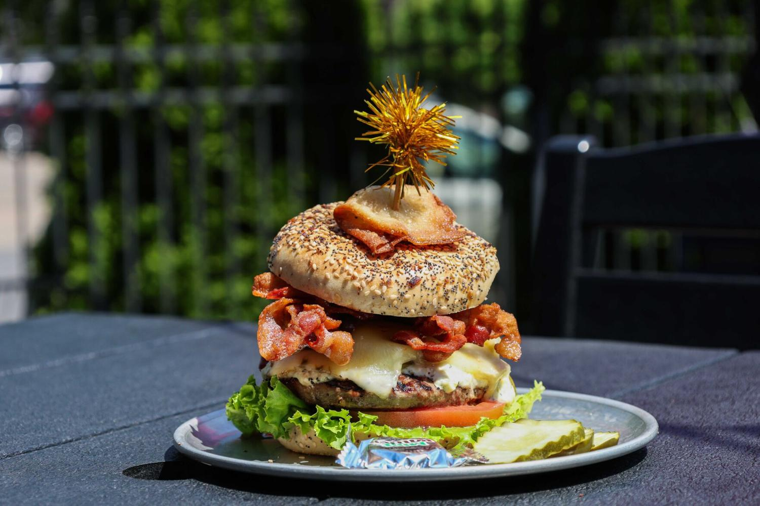 Tall seeded bun burger with bacon and melted cheese stacked high from Licari's Bar and Grill in Madison