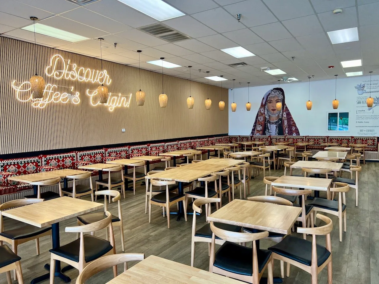 Interior of Qamaria Yemeni Coffee with neon Discover Coffee's Origin sign and mural