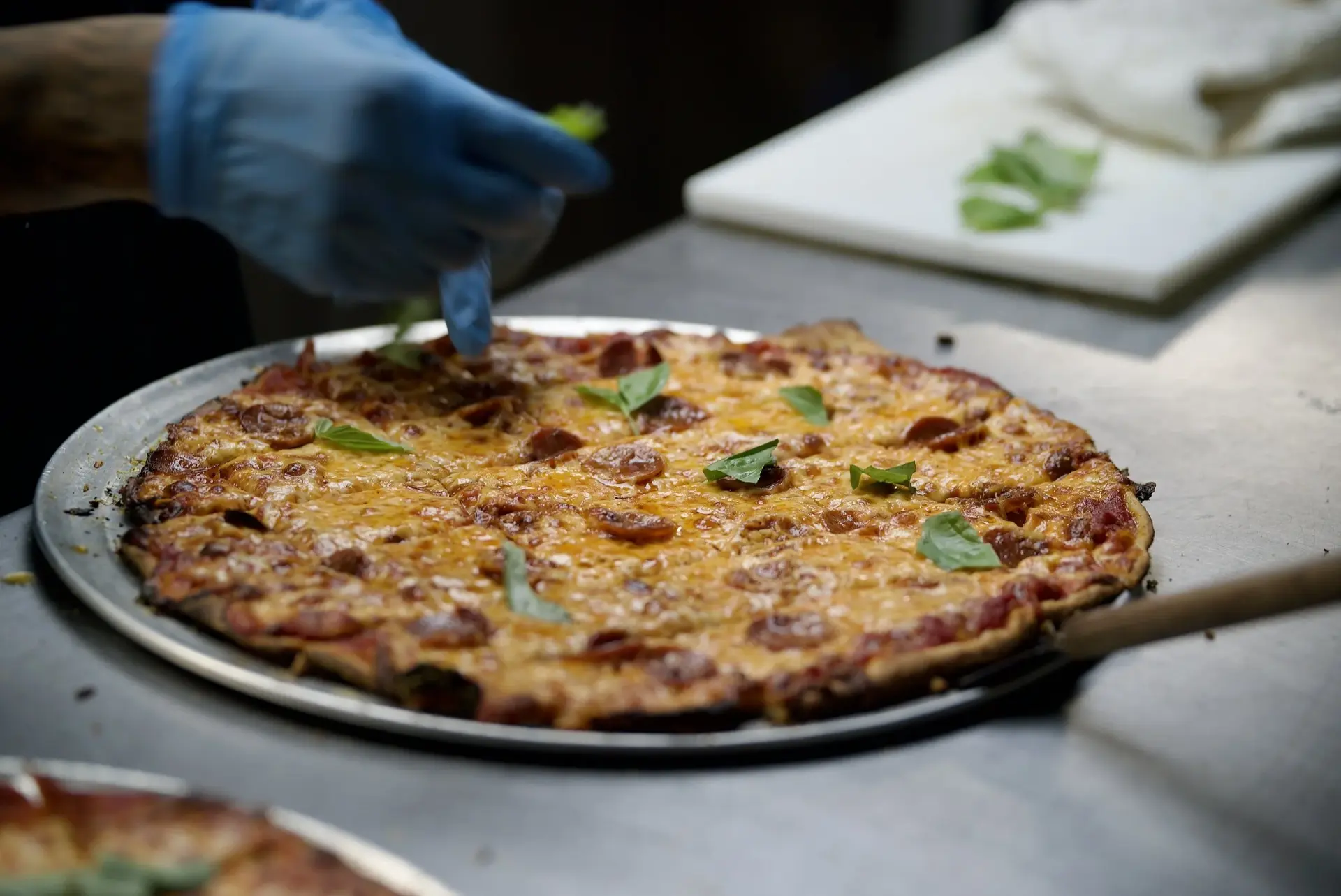 Pepperoni pizza being finished with fresh basil in the kitchen at Greenbush Bar on Regent Street in Madison, Wisconsin