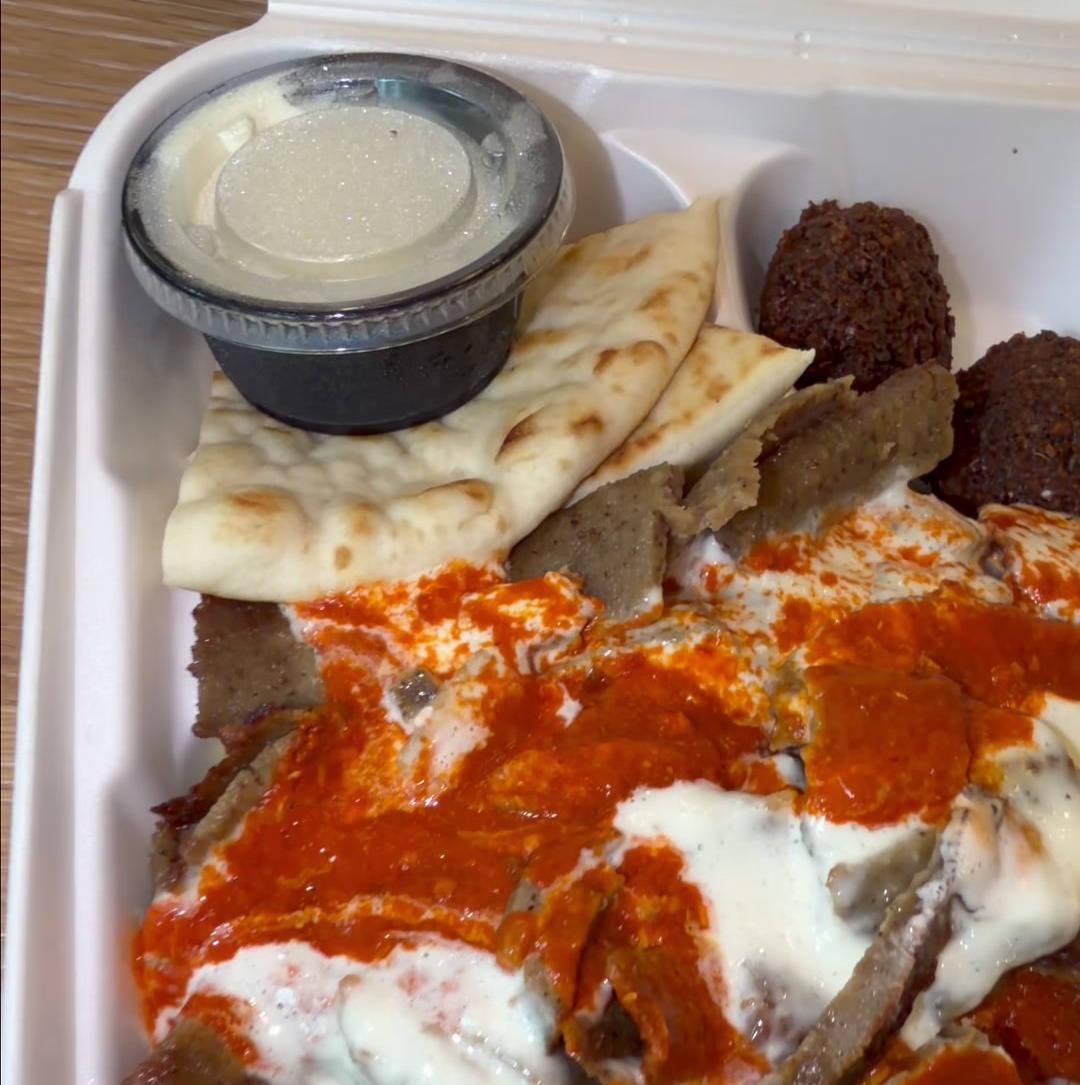 Gyro rice bowl with gyro meat, white sauce, spicy red sauce, pita, and falafel in a takeout box from Gyro Guyz in Madison