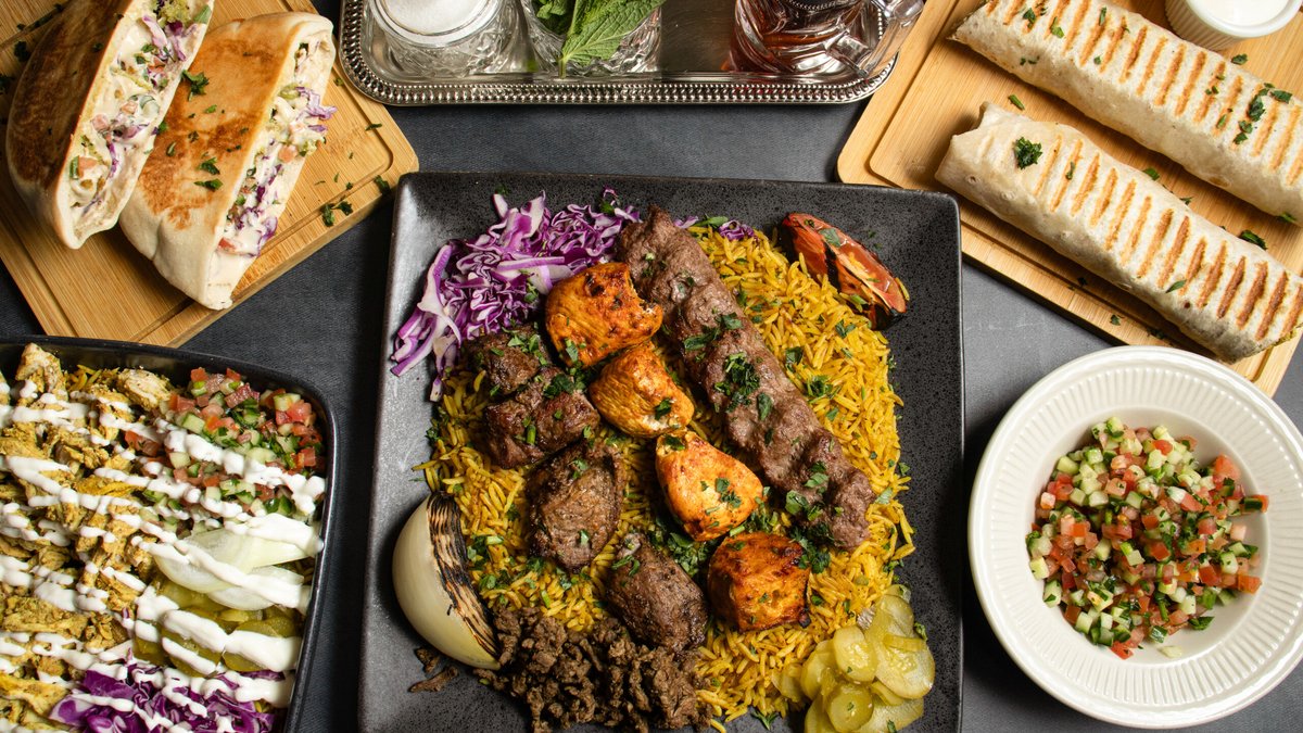 Mixed kebab platter over yellow rice with wraps, stuffed pitas, a chicken shawarma bowl, and salad from Petra Bakery and Restaurant on Odana Road in Madison