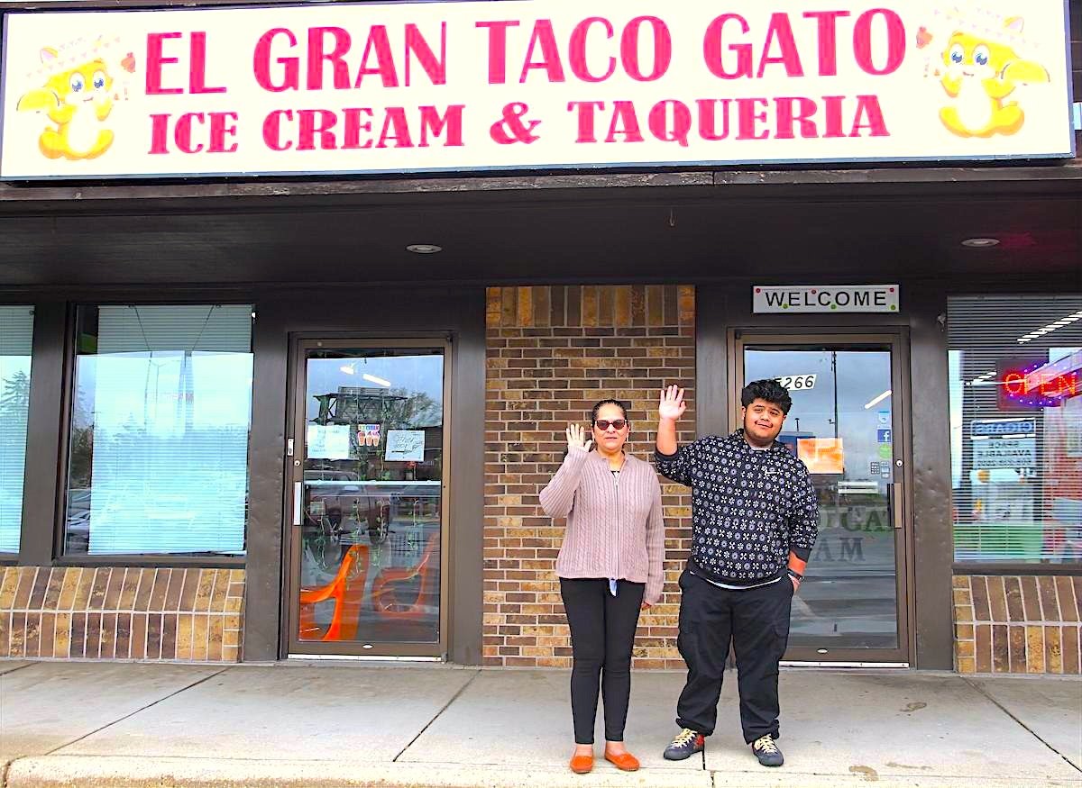 Owners waving outside the El Gran Taco Gato storefront in Fitchburg