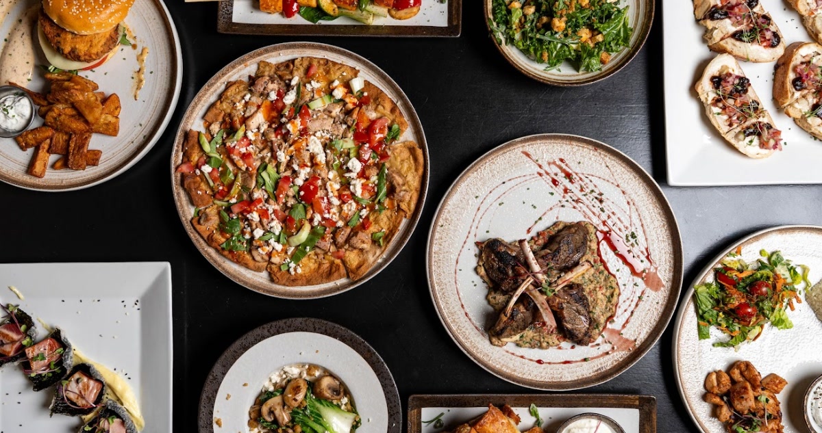 Overhead spread of Mediterranean dishes including lamb, flatbread, salads, and bruschetta at Eloura in downtown Madison