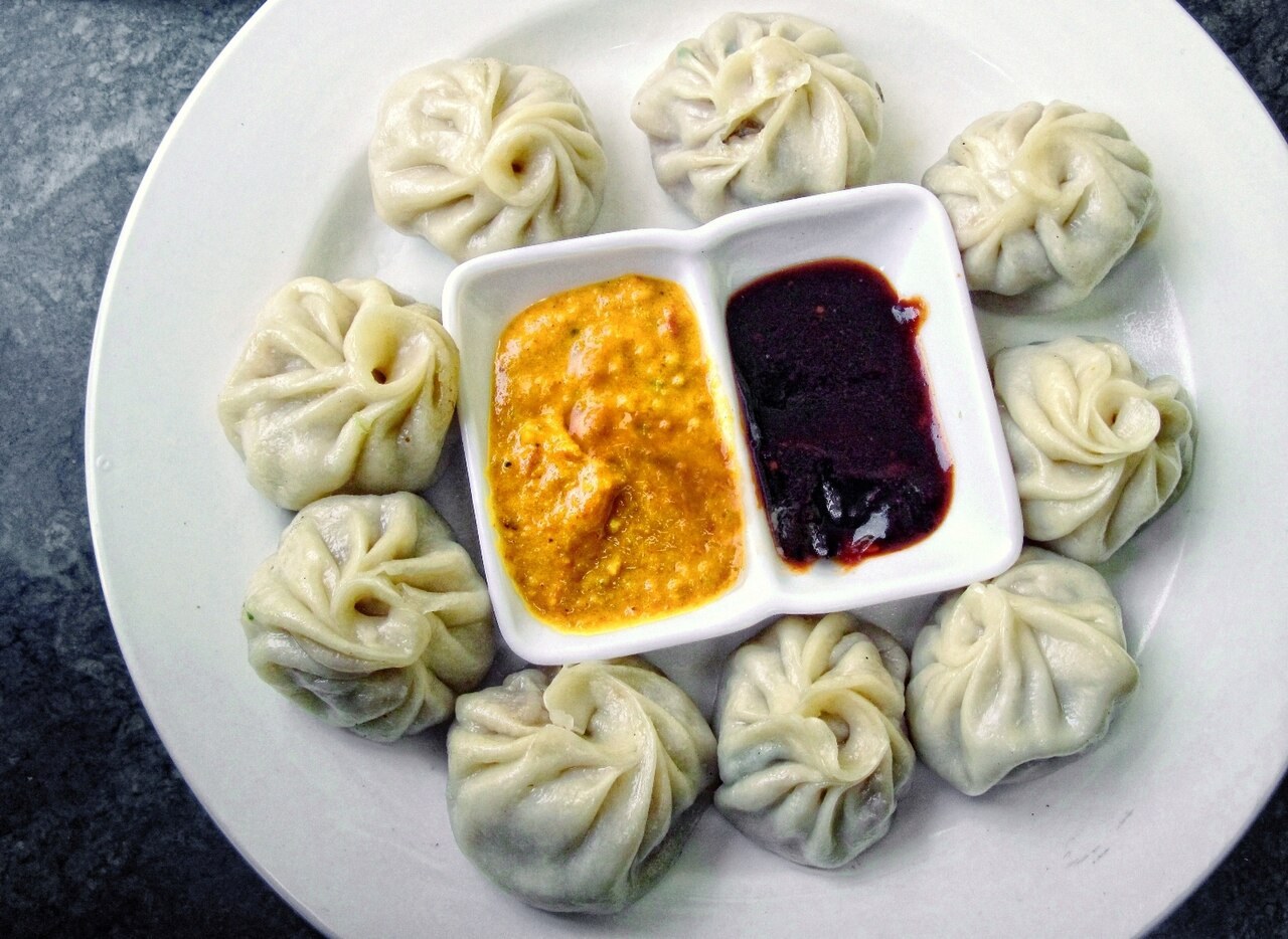 Plate of steamed Tibetan momo dumplings with two dipping sauces