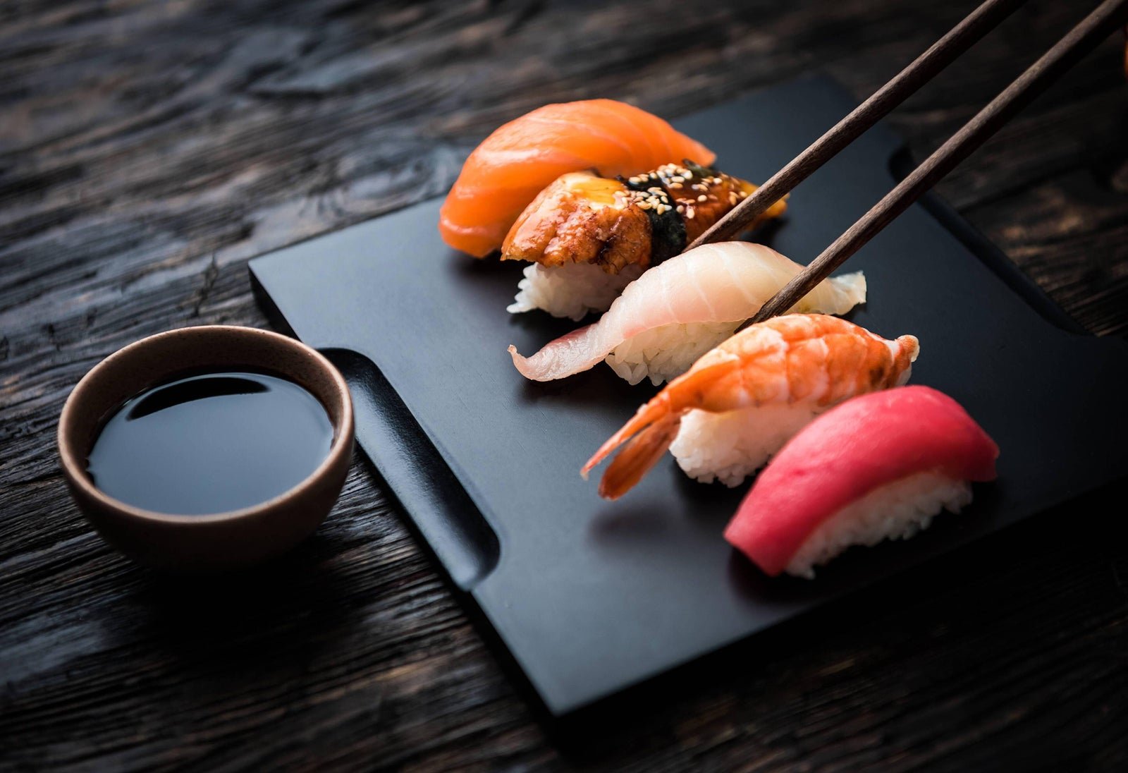 Assorted nigiri sushi on a black plate at Miyabi Sushi in Fitchburg