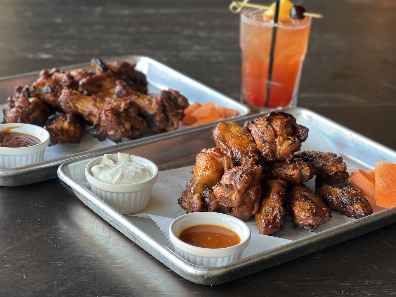Two trays of grilled wings with dipping sauces at Neighborhood Draft in Milwaukee, Wisconsin